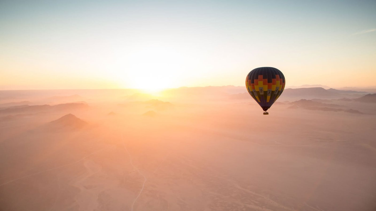 Sunrise hot-air balloon over the red dunes