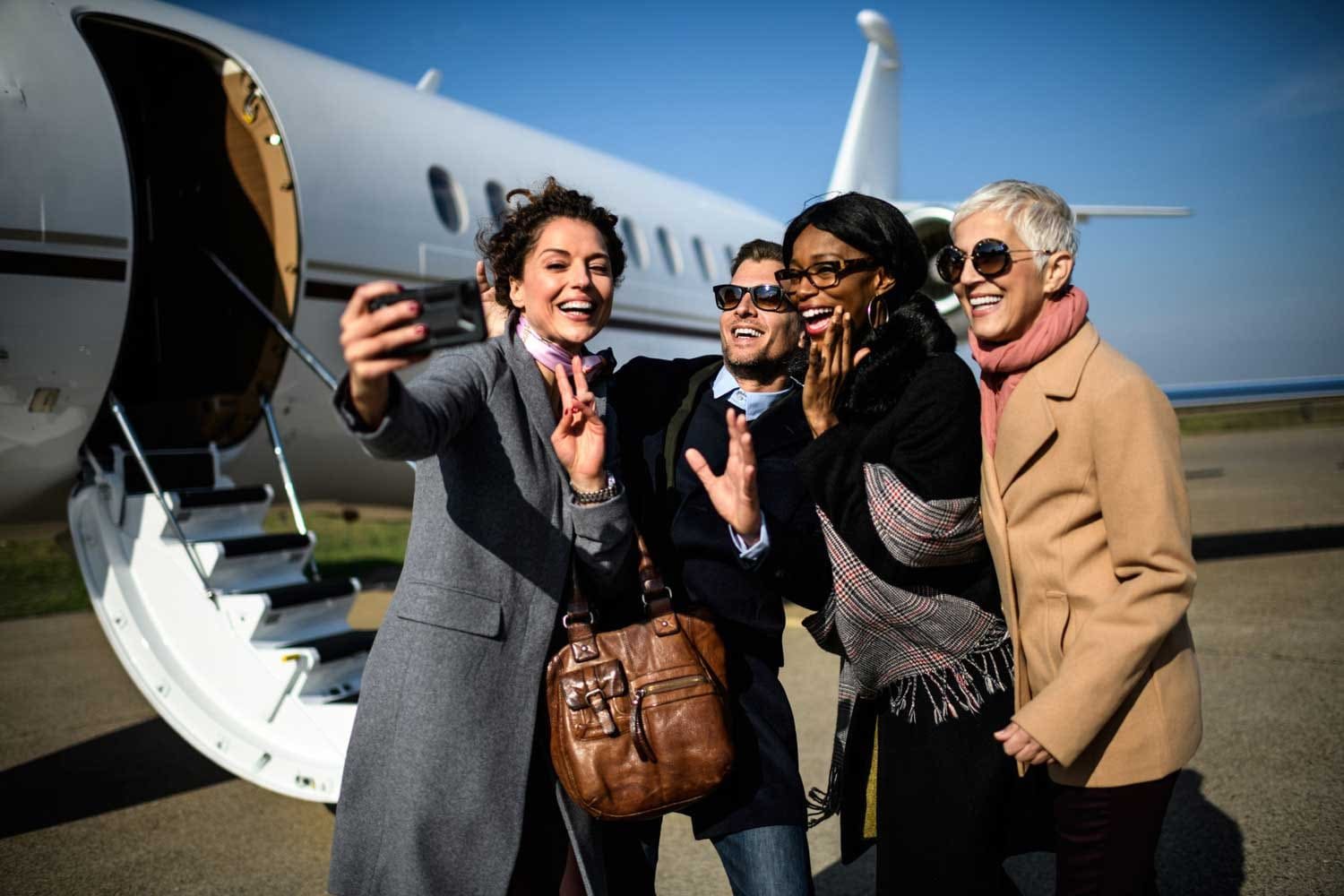 A group of friends celebrating beside their private jet